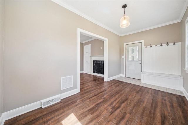 interior space featuring crown molding, baseboards, wood finished floors, and visible vents