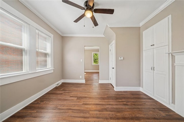 empty room featuring crown molding, baseboards, and dark wood finished floors