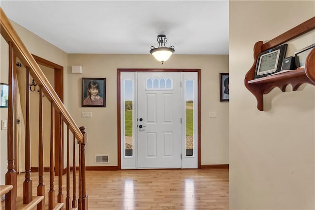 foyer with baseboards, visible vents, light wood-style flooring, and stairway
