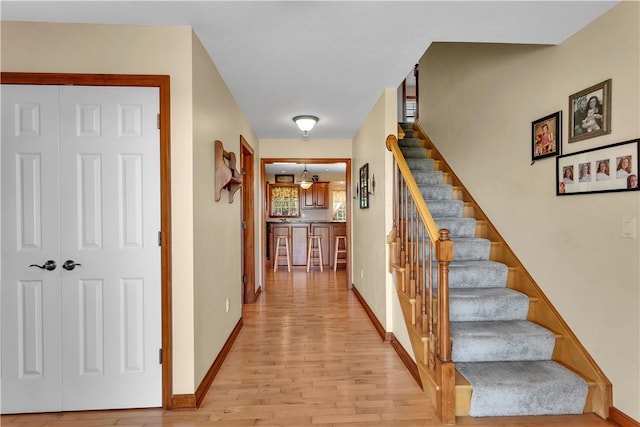 staircase featuring baseboards, a notable chandelier, and wood finished floors