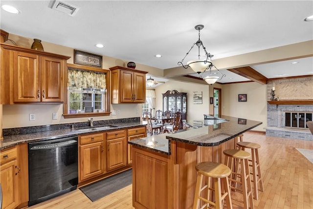 kitchen featuring a kitchen breakfast bar, visible vents, dishwasher, a sink, and light wood-style flooring