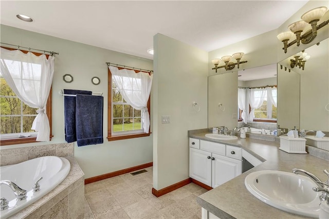 bathroom with double vanity, a sink, a bath, and a wealth of natural light