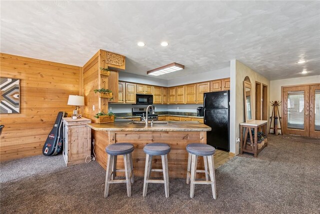 kitchen featuring light colored carpet, a sink, a peninsula, recessed lighting, and black appliances