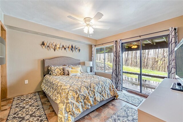 bedroom featuring a ceiling fan, stone finish floor, and access to exterior