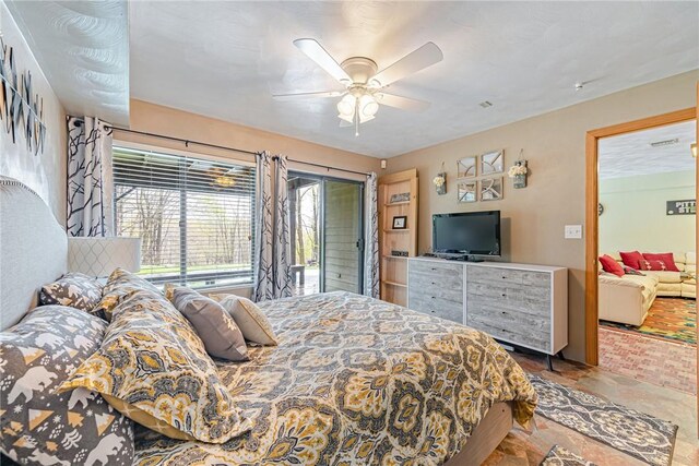 bedroom with a ceiling fan, stone finish floor, and access to exterior
