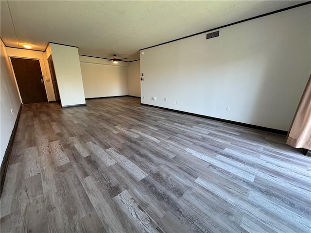 interior space featuring baseboards, ceiling fan, wood finished floors, and visible vents