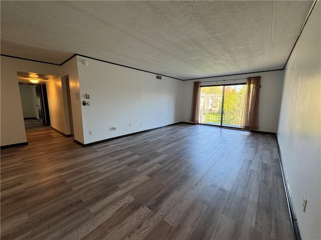 spare room with baseboards, a textured ceiling, wood finished floors, and visible vents