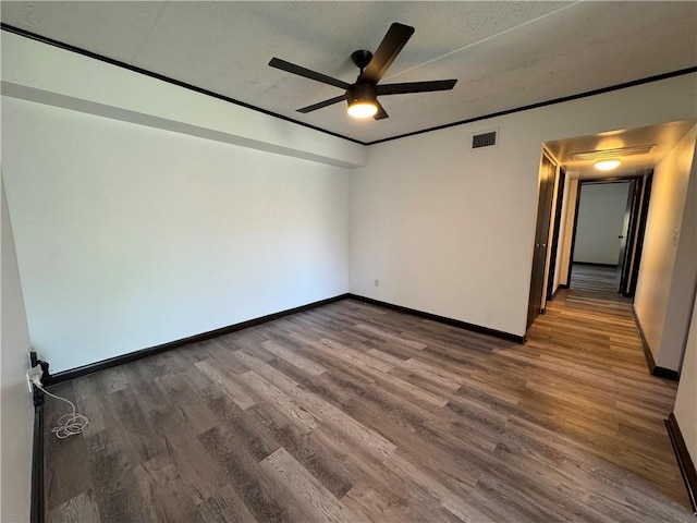 empty room with baseboards, a ceiling fan, wood finished floors, and visible vents
