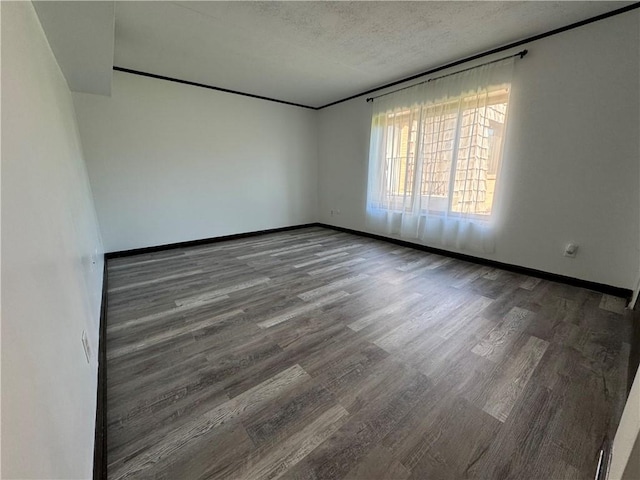 unfurnished room featuring baseboards, a textured ceiling, and wood finished floors