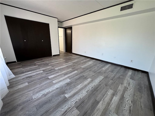 unfurnished bedroom with baseboards, wood finished floors, and visible vents