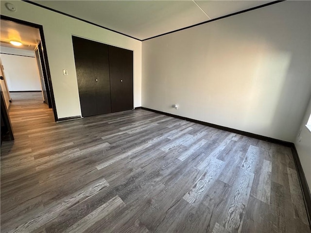 unfurnished bedroom featuring baseboards, a closet, and wood finished floors