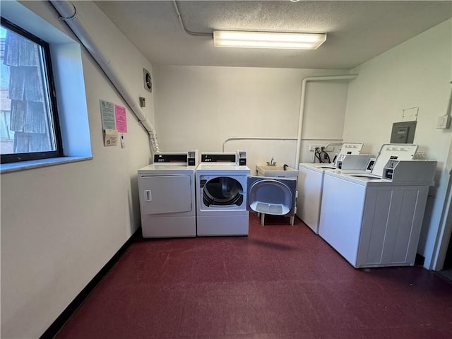 community laundry room with a sink, carpet, electric panel, and washing machine and clothes dryer