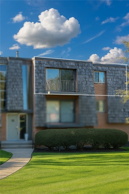 contemporary house with mansard roof, a front lawn, and a balcony