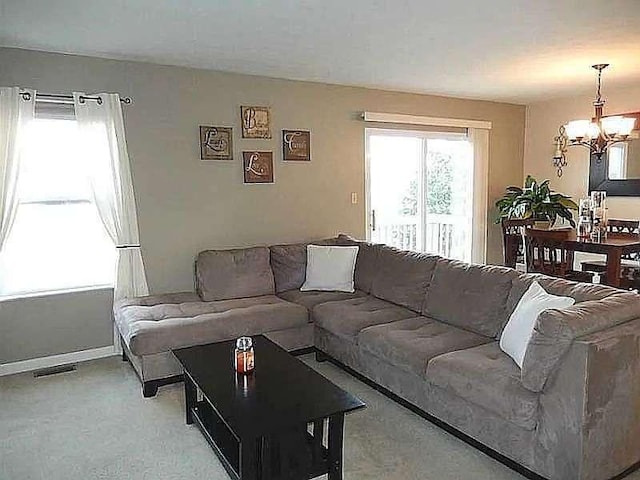 living area featuring light colored carpet, baseboards, a chandelier, and visible vents
