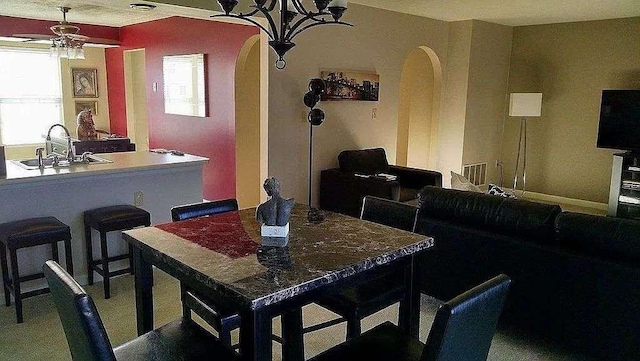 carpeted dining area with a sink, a ceiling fan, and arched walkways
