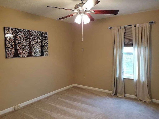 spare room featuring a ceiling fan, baseboards, and light colored carpet