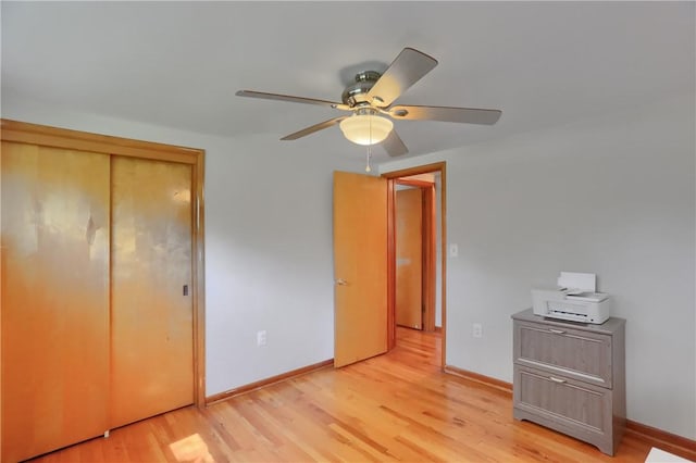 unfurnished bedroom featuring baseboards, a ceiling fan, light wood finished floors, and a closet