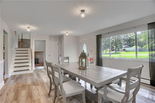 dining room with a brick fireplace and light wood finished floors