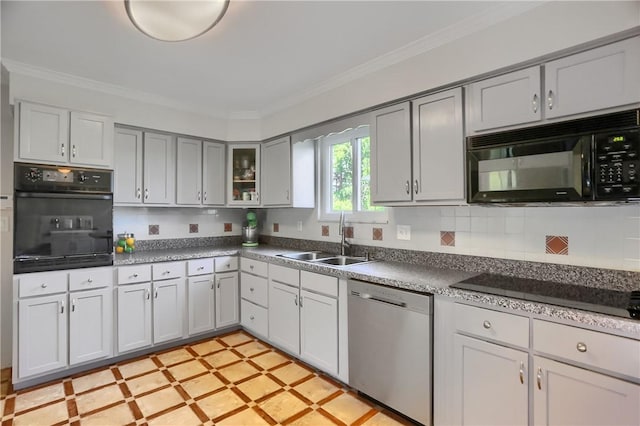 kitchen with dark countertops, a sink, black appliances, glass insert cabinets, and ornamental molding