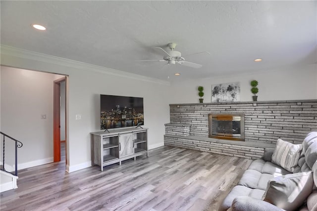 living room featuring ceiling fan, stairs, baseboards, wood finished floors, and ornamental molding
