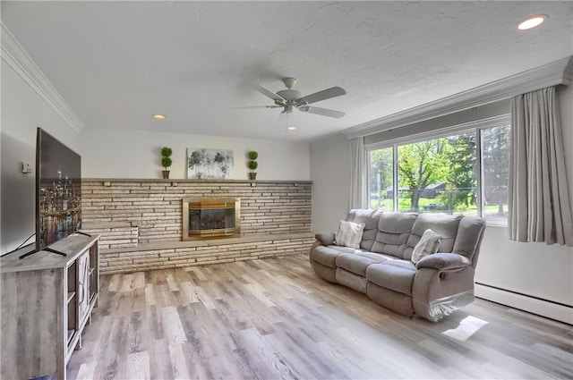 living room featuring ornamental molding, a brick fireplace, wood finished floors, ceiling fan, and a baseboard radiator