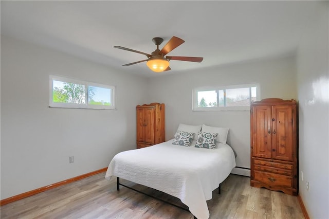 bedroom with baseboards, a ceiling fan, a baseboard heating unit, and light wood finished floors