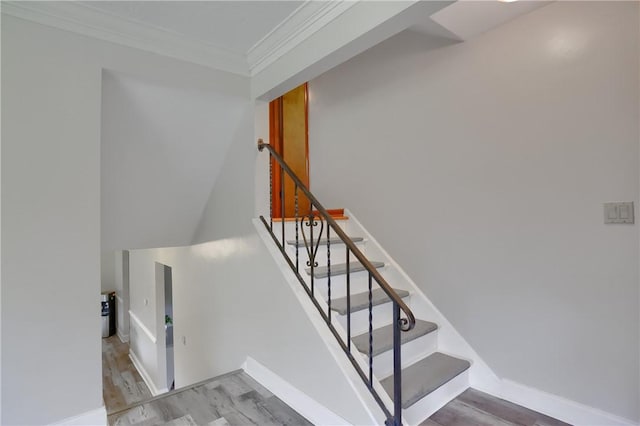 stairs featuring baseboards, ornamental molding, and wood finished floors
