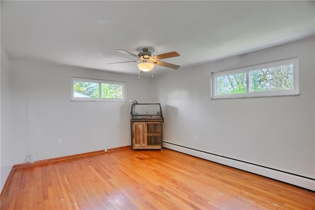 spare room featuring light wood-type flooring, a baseboard radiator, baseboards, and ceiling fan