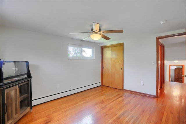 unfurnished bedroom with ceiling fan, baseboard heating, baseboards, a closet, and light wood-style flooring