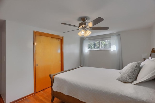 bedroom with a ceiling fan, baseboards, and light wood-type flooring