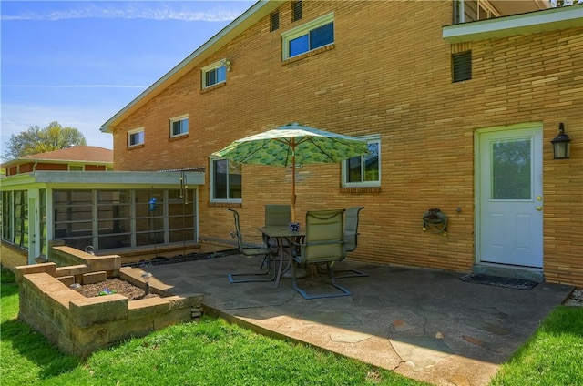 back of house featuring a sunroom, a patio area, and brick siding