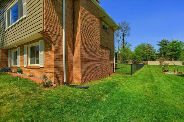 view of side of home featuring a lawn and fence