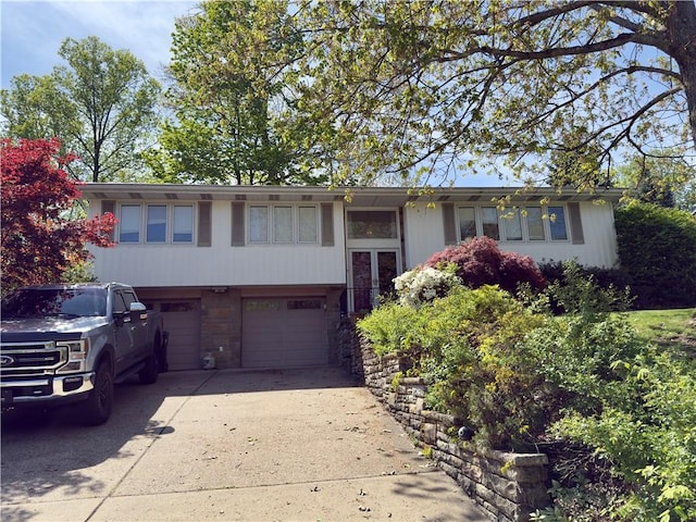 split foyer home featuring driveway, stone siding, and a garage