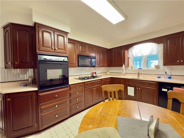 kitchen with decorative backsplash, light floors, light countertops, a sink, and black appliances