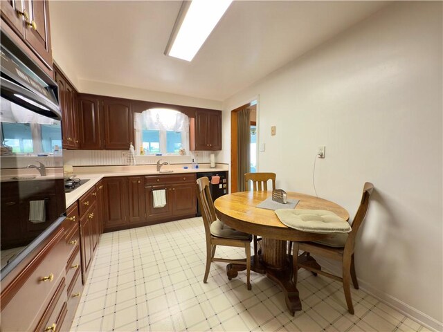 kitchen with light countertops, light floors, multiple ovens, and black cooktop
