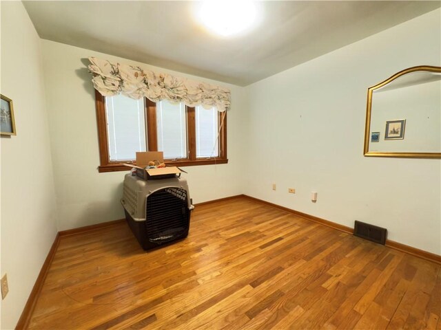 unfurnished room featuring baseboards, light wood-style flooring, and visible vents