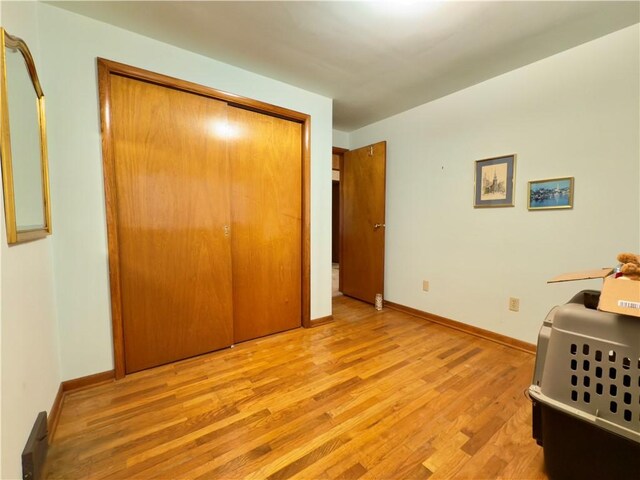 bedroom with light wood-style floors, baseboards, and a closet