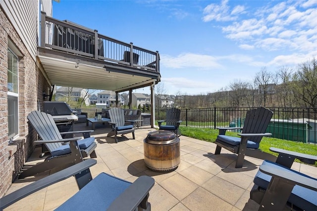 view of patio with fence, a fire pit, and a balcony