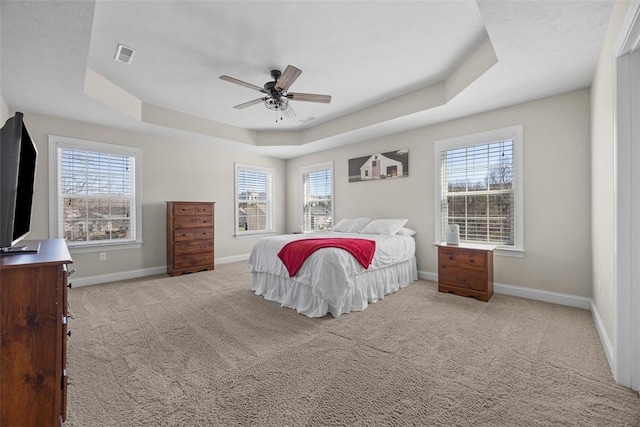 bedroom with multiple windows, a tray ceiling, and visible vents