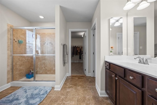 full bath with baseboards, a stall shower, and vanity
