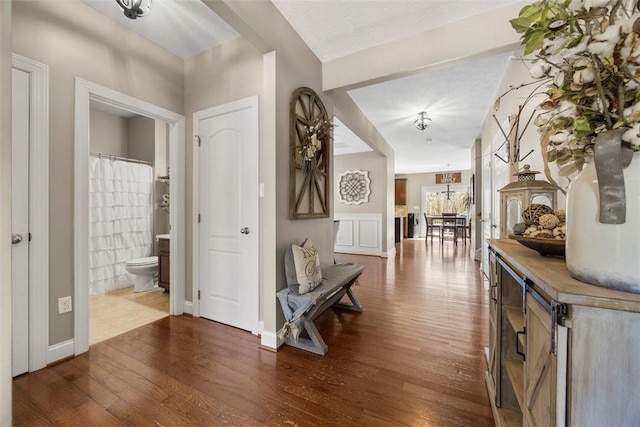 hallway featuring baseboards, dark wood-style flooring, and a notable chandelier