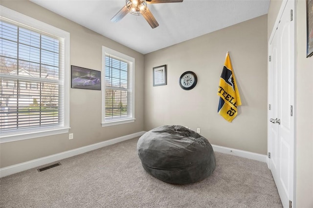 living area featuring baseboards, carpet, a ceiling fan, and visible vents