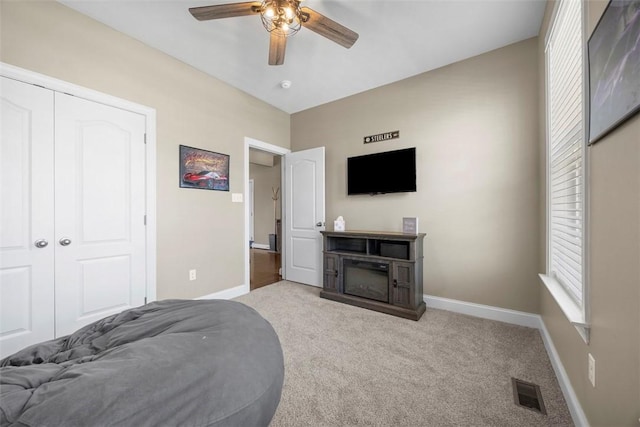 bedroom featuring a glass covered fireplace, baseboards, carpet, and visible vents
