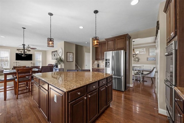kitchen with a center island, open floor plan, appliances with stainless steel finishes, and dark wood-type flooring