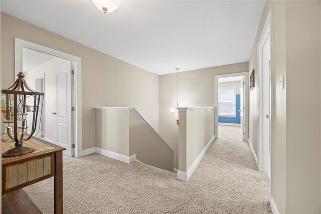 hall with carpet floors, baseboards, and an upstairs landing
