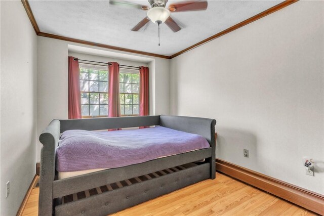 bedroom featuring ceiling fan, crown molding, wood finished floors, baseboards, and a baseboard heating unit