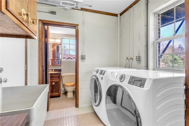 laundry area with plenty of natural light, cabinet space, light tile patterned floors, and washer and dryer