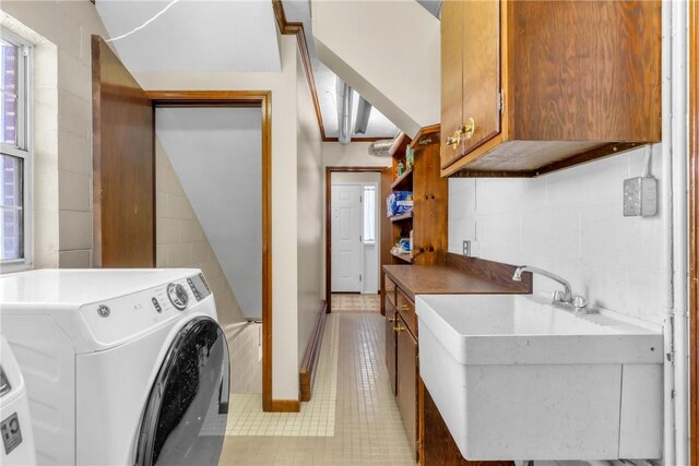 clothes washing area with a sink, cabinet space, light tile patterned flooring, and washer / clothes dryer