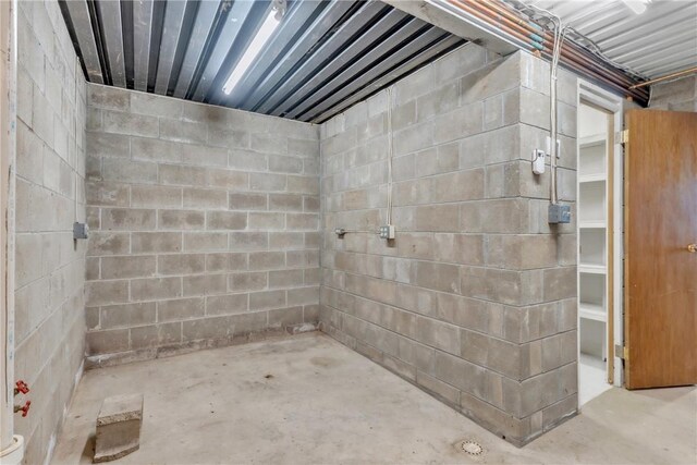 bathroom with concrete block wall and unfinished concrete floors