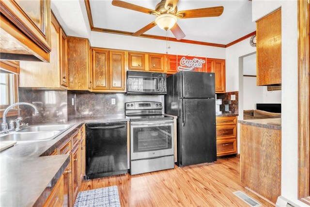 kitchen with ceiling fan, brown cabinetry, a sink, black appliances, and light wood finished floors